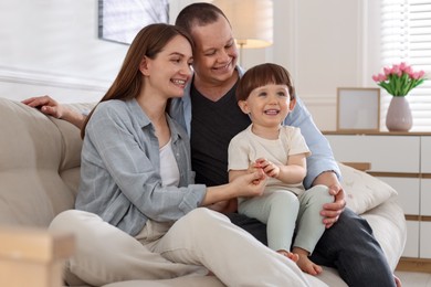 Photo of Cute little boy and his parents on sofa at home. Lovely family