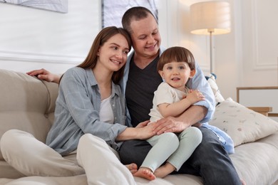 Photo of Cute little boy and his parents on sofa at home. Lovely family