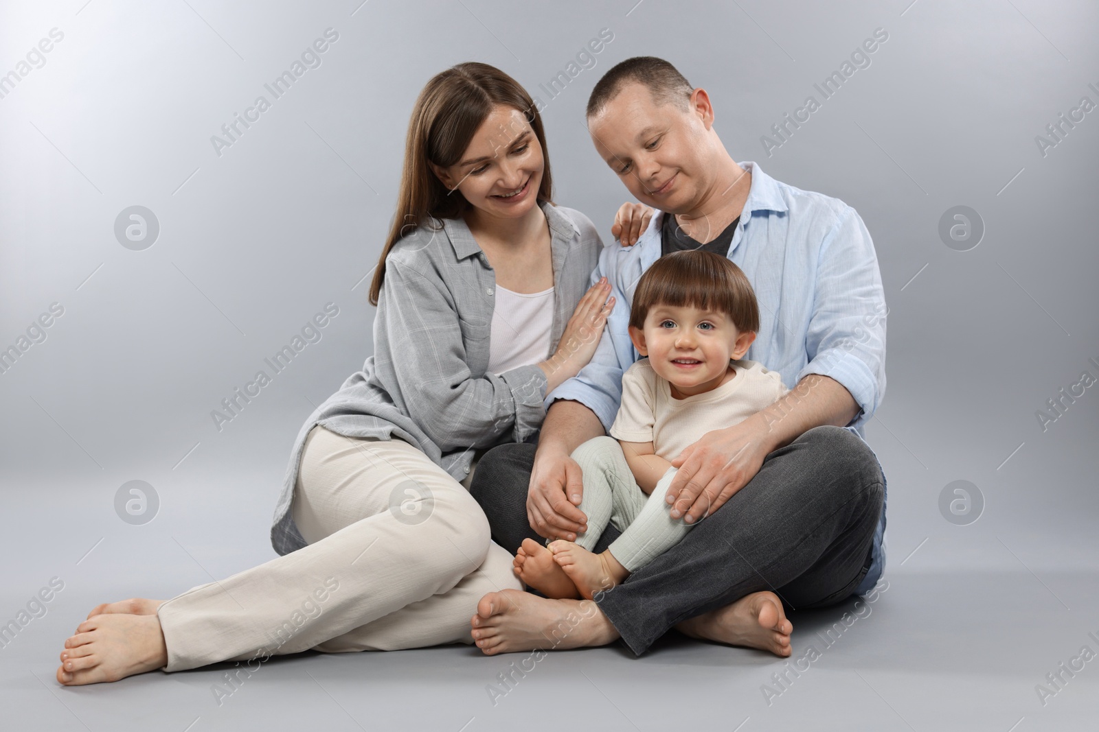 Happy parents and their baby boy on light grey background. Lovely family Photo of Happy parents and their baby boy on light grey background. Lovely family