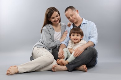 Photo of Happy parents and their baby boy on light grey background. Lovely family