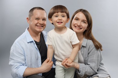Photo of Happy parents and their baby boy on light grey background. Lovely family