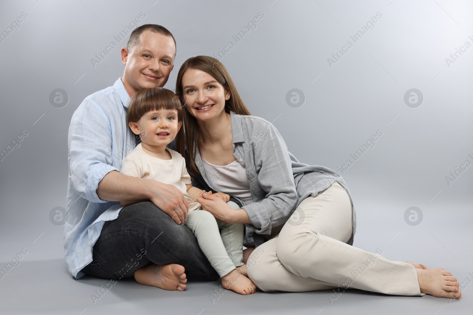 Happy parents and their baby boy on light grey background. Lovely family Photo of Happy parents and their baby boy on light grey background. Lovely family