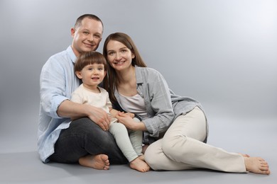 Photo of Happy parents and their baby boy on light grey background. Lovely family