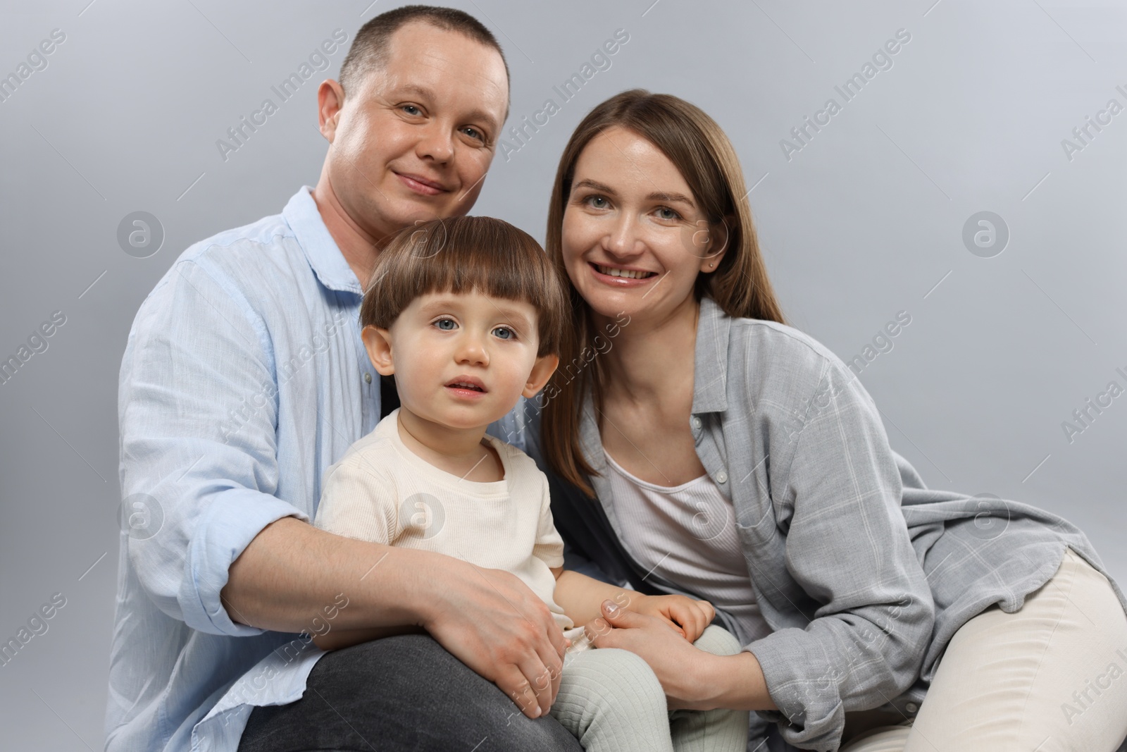 Happy parents and their baby boy on light grey background. Lovely family Photo of Happy parents and their baby boy on light grey background. Lovely family