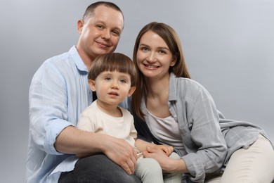 Photo of Happy parents and their baby boy on light grey background. Lovely family