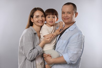 Photo of Happy parents and their baby boy on light grey background. Lovely family