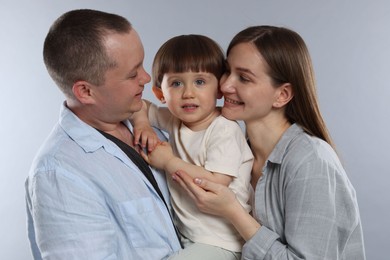 Photo of Happy parents and their baby boy on light grey background. Lovely family