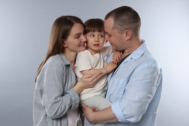 Photo of Happy parents and their baby boy on light grey background. Lovely family