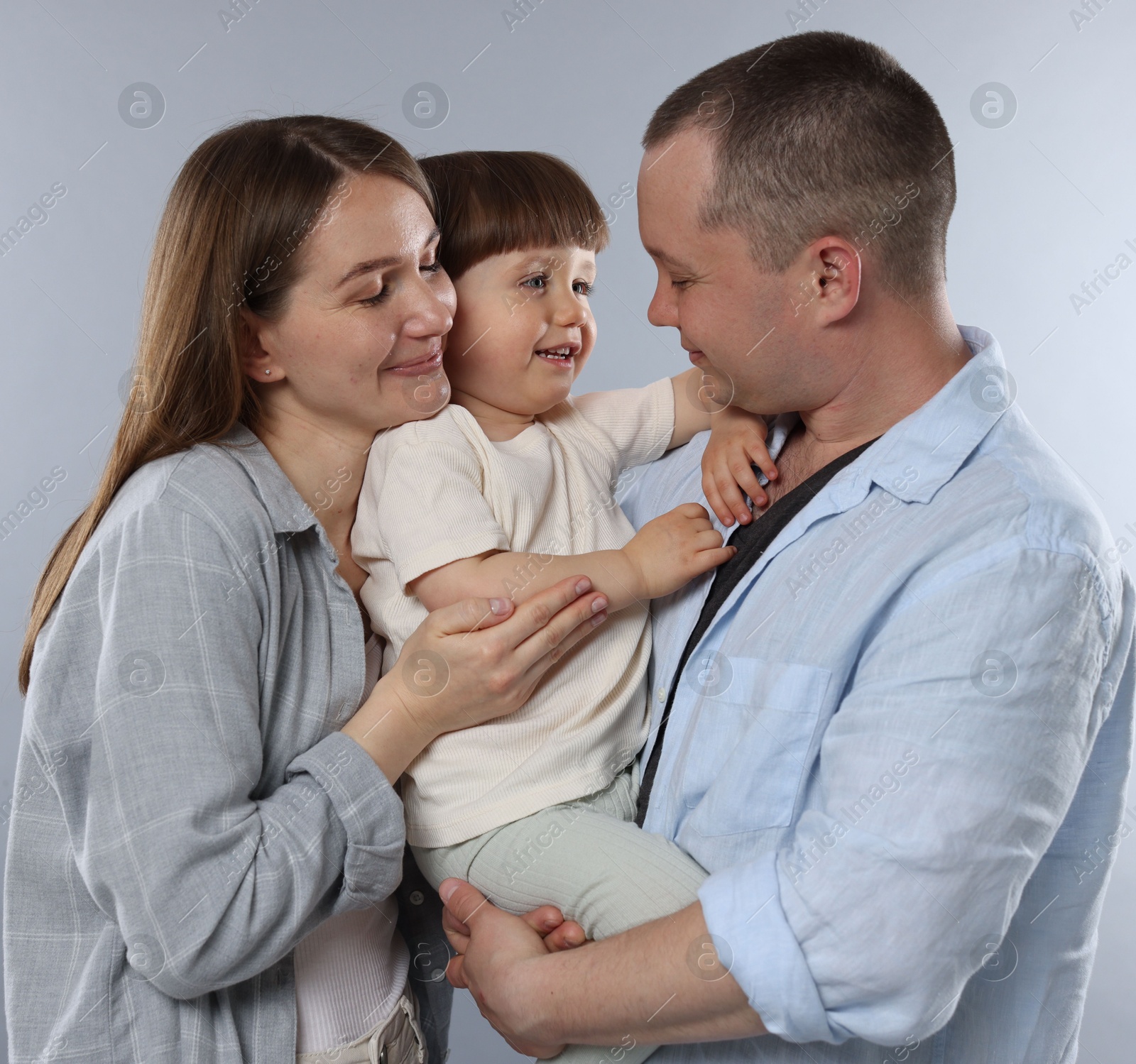 Happy parents and their baby boy on light grey background. Lovely family Photo of Happy parents and their baby boy on light grey background. Lovely family