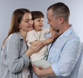 Photo of Happy parents and their baby boy on light grey background. Lovely family