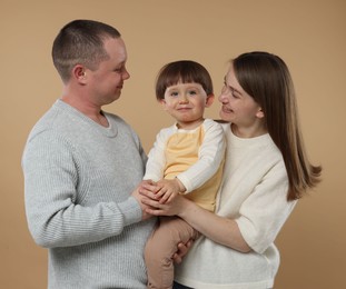 Photo of Happy parents and their baby boy on beige background. Lovely family