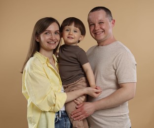 Photo of Happy parents and their baby boy on beige background. Lovely family