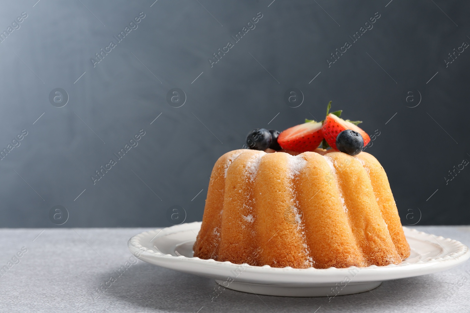 Tasty Bundt cake with powdered sugar and berries on light grey table, closeup. Space for text Photo of Tasty Bundt cake with powdered sugar and berries on light grey table, closeup. Space for text