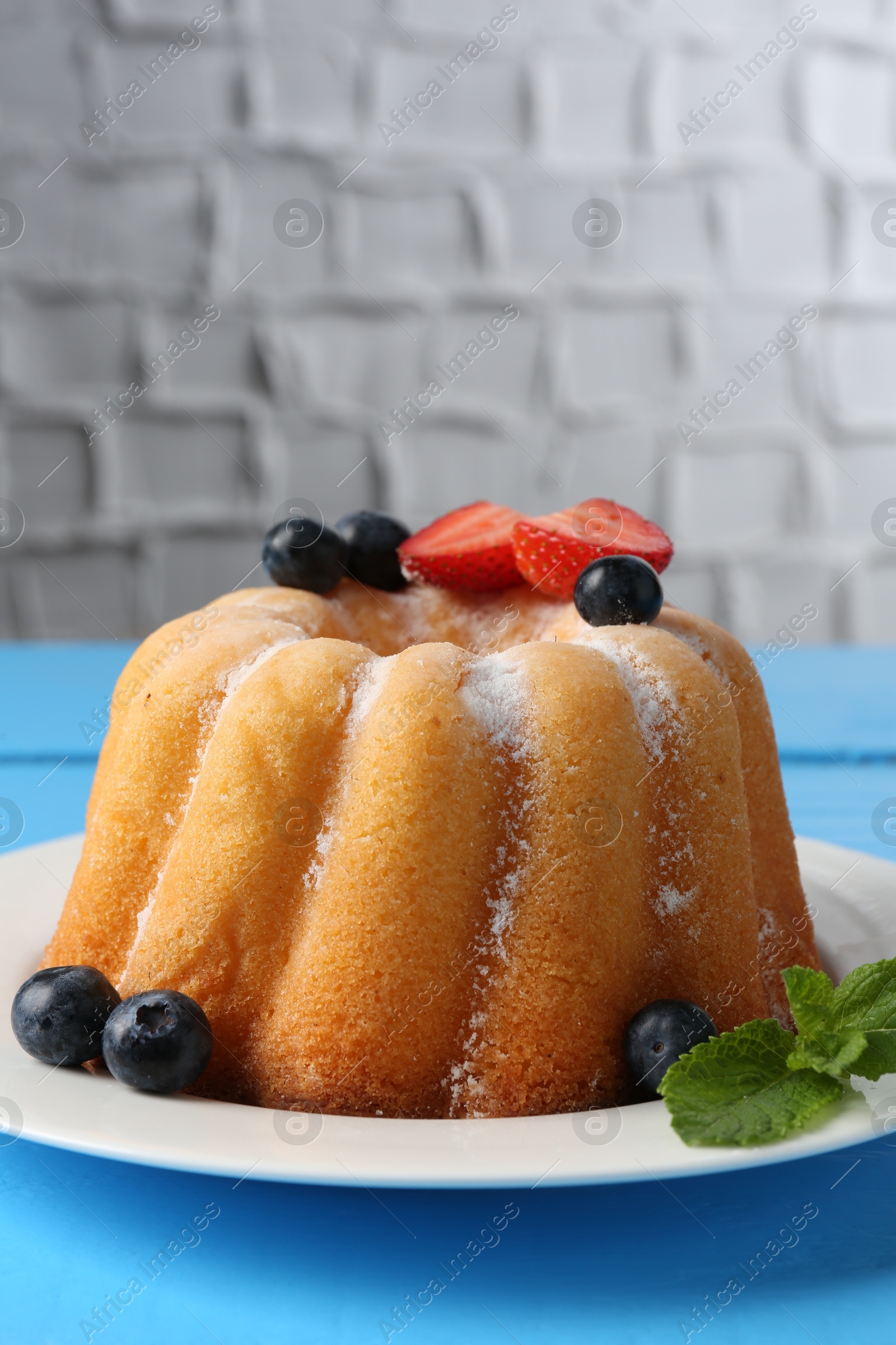 Tasty Bundt cake with powdered sugar and berries on light blue wooden table, closeup. Space for text Photo of Tasty Bundt cake with powdered sugar and berries on light blue wooden table, closeup. Space for text