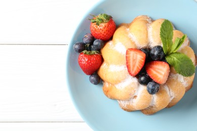 Photo of Tasty Bundt cake with powdered sugar and berries on white wooden table, top view. Space for text