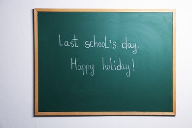 Photo of Phrases Last School's Day and Happy Holiday with exclamation mark on blackboard