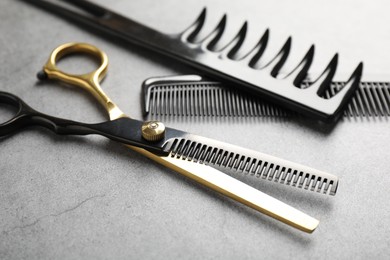 Photo of Different hairdresser's tools on grey table, closeup