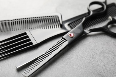 Photo of Different hairdresser's tools on grey table, closeup
