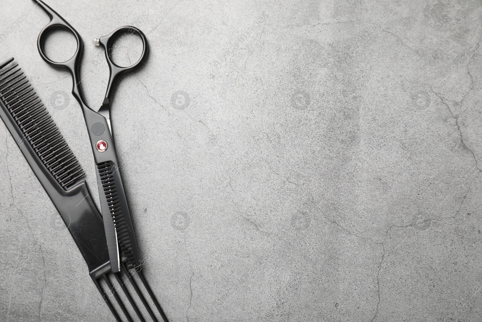 Hairdresser's tools. Scissors and comb on grey table, flat lay. Space for text Photo of Hairdresser's tools. Scissors and comb on grey table, flat lay. Space for text