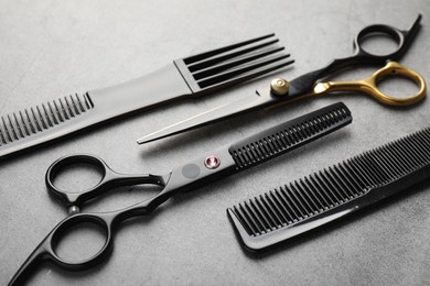 Photo of Different hairdresser's tools on grey table, closeup