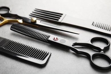 Photo of Different hairdresser's tools on grey table, closeup