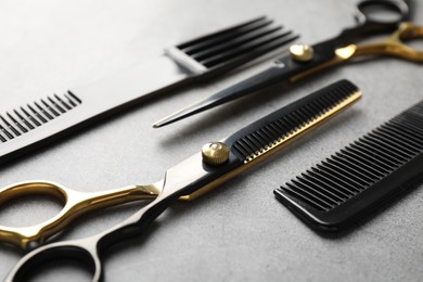 Photo of Different hairdresser's tools on grey table, closeup