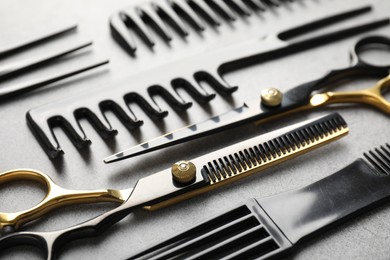 Photo of Different hairdresser's tools on grey table, closeup