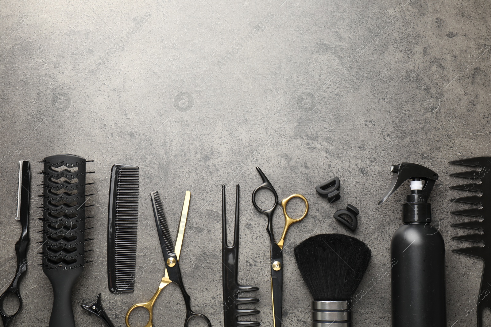Different hairdresser's tools on grey table, flat lay. Space for text Photo of Different hairdresser's tools on grey table, flat lay. Space for text