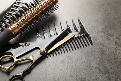Photo of Different hairdresser's tools on grey table, closeup