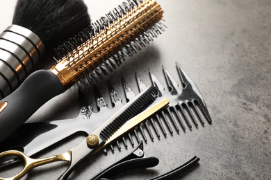 Photo of Different hairdresser's tools on grey table, closeup