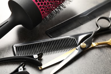 Photo of Different hairdresser's tools on grey table, closeup