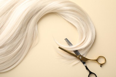 Photo of Hair lock and scissors on beige background, flat lay