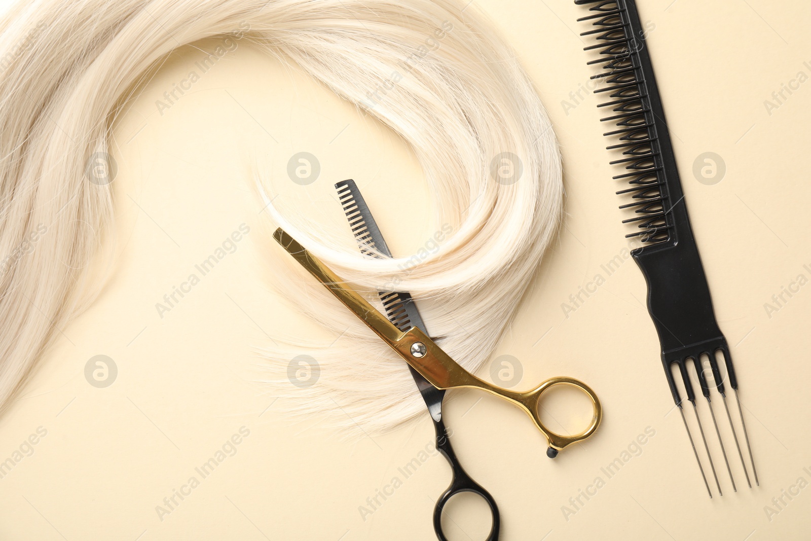 Hair lock, comb and scissors on beige background, flat lay Photo of Hair lock, comb and scissors on beige background, flat lay