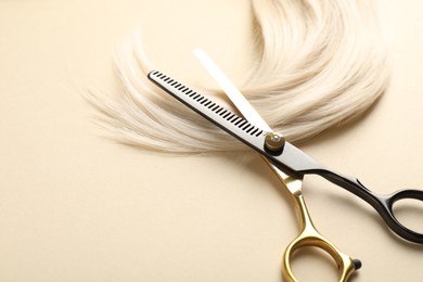 Photo of Hair lock and scissors on beige background, above view. Space for text