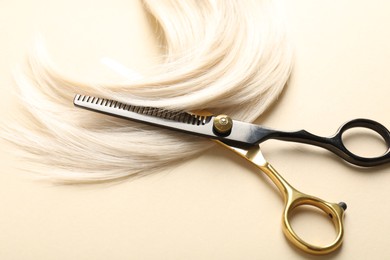 Photo of Hair lock and scissors on beige background, above view