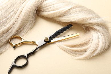 Photo of Hair lock and scissors on beige background, above view