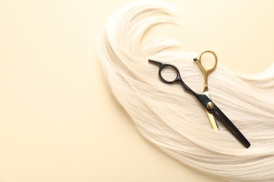 Photo of Hair lock and scissors on beige background, top view. Space for text