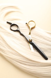 Photo of Hair lock and scissors on beige background, above view