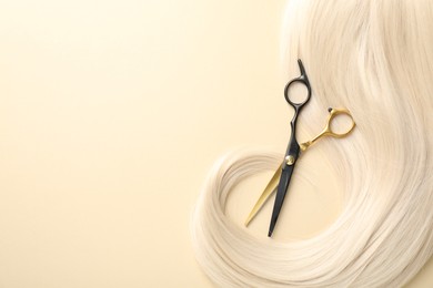Photo of Hair lock and scissors on beige background, top view. Space for text
