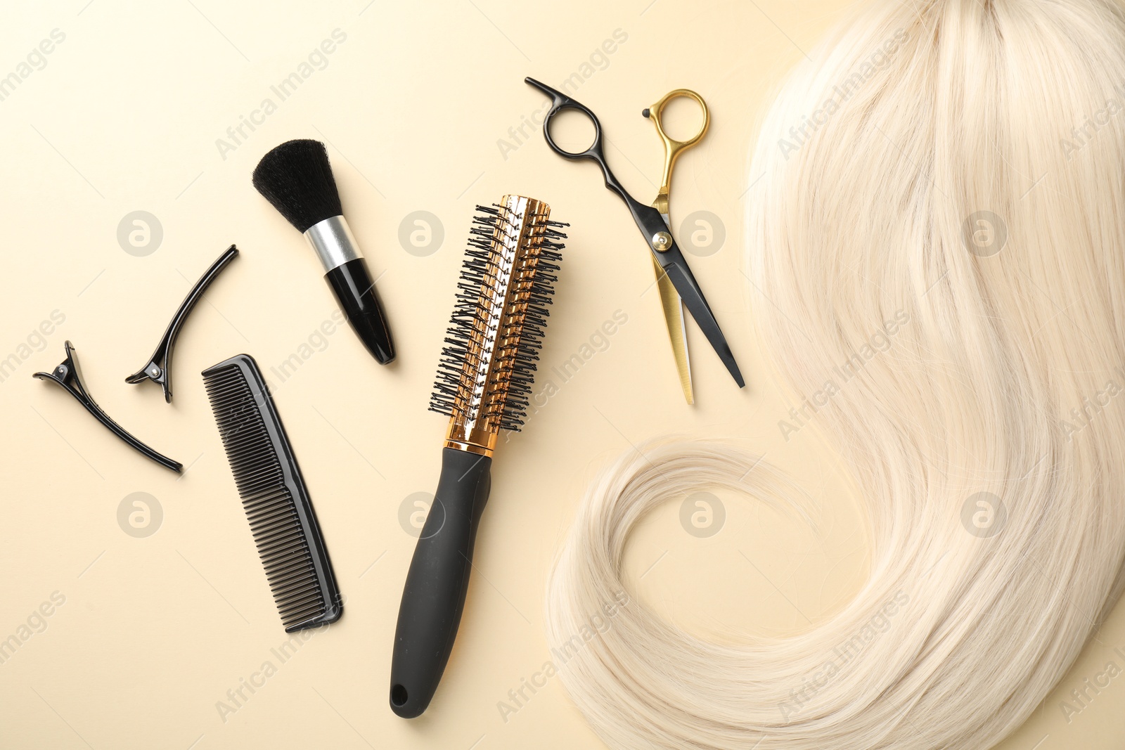 Hair lock and different hairdresser's tools on beige background, flat lay Photo of Hair lock and different hairdresser's tools on beige background, flat lay