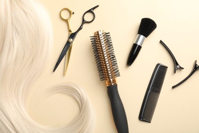 Photo of Hair lock and different hairdresser's tools on beige background, flat lay