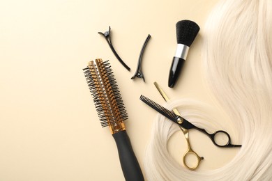 Photo of Hair lock and different hairdresser's tools on beige background, flat lay. Space for text