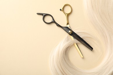 Photo of Hair lock and scissors on beige background, flat lay. Space for text