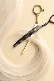 Photo of Hair lock and scissors on beige background, flat lay