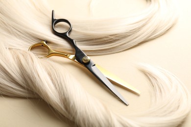Photo of Hair locks and scissors on beige background, closeup