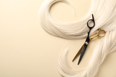 Photo of Hair locks and scissors on beige background, flat lay. Space for text