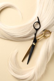 Photo of Hair locks and scissors on beige background, flat lay