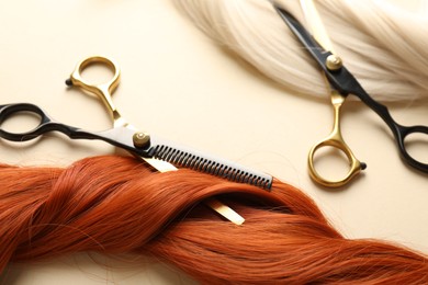 Photo of Hair locks and scissors on beige background, closeup