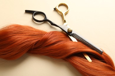 Photo of Hair lock and scissors on beige background, above view