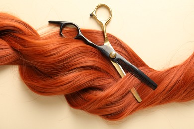 Photo of Hair lock and scissors on beige background, top view